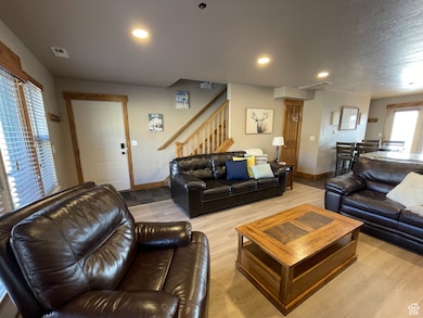 Living area with light wood finished floors, stairway, recessed lighting, and a textured ceiling