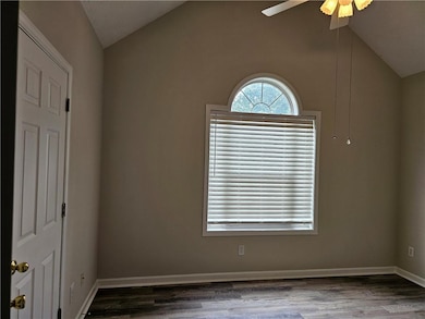 Empty room featuring vaulted ceiling, ceiling fan, wood finished floors, and baseboards