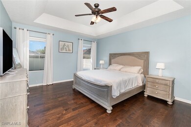 Bedroom with a ceiling fan, a tray ceiling, basebo