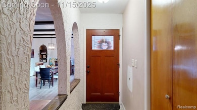 Foyer featuring arched walkways, beamed ceiling, a textured wall, and wood finished floors