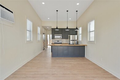 Kitchen with hanging light fixtures, tasteful backsplash, butcher block counters, appliances with stainless steel finishes, and recessed lighting