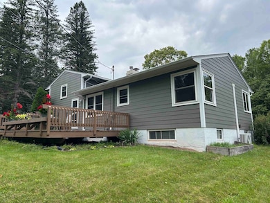 Back of house featuring a lawn, a deck, and a chimney