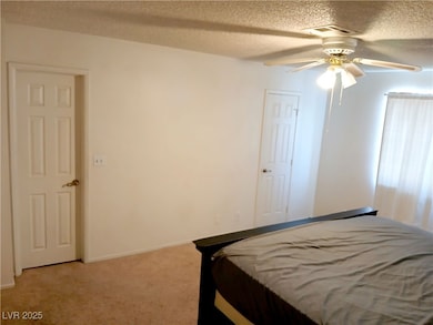 Bedroom featuring light carpet, ceiling fan.