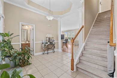 Entryway with light tile patterned floors, stairway, baseboards, and ornate columns