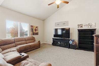 Living room featuring carpet floors, high vaulted ceiling, and ceiling fan