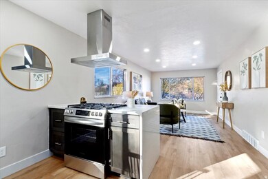 Kitchen featuring stainless steel gas range oven, light wood-type flooring, island range hood, light stone countertops, and recessed lighting