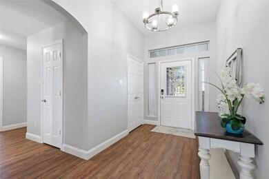 Entryway featuring dark wood finished floors, arched walkways, and a chandelier