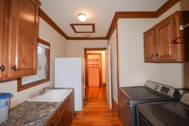 Washroom with crown molding, cabinet space, light wood-type flooring, and washing machine and dryer