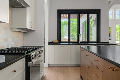 Kitchen with wall chimney range hood, a sink, dar