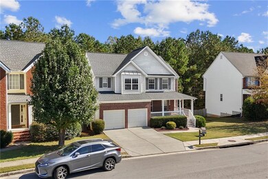 Traditional-style home with driveway, brick siding, an attached garage, a shingled roof, and a front lawn