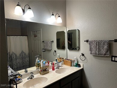 Bathroom with double vanity, a textured wall, and
