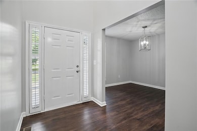 Foyer entrance with dark wood-type flooring, a chandelier, and a textured ceiling