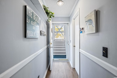 Doorway featuring a textured ceiling, crown moldin