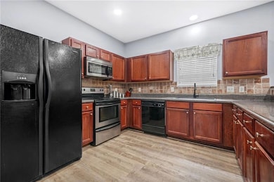 Kitchen with dark countertops, light wood-style fl