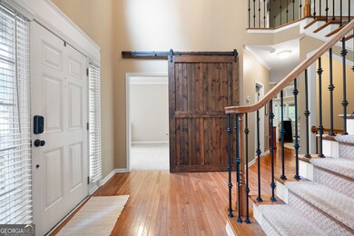 Two-story foyer with sliding barn door leading to main level bedroom