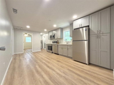 Kitchen featuring stainless steel appliances, gray cabinetry, light wood-style flooring, a ceiling fan, and recessed lighting