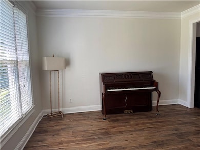 Living area with healthy amount of natural light, dark wood-type flooring, crown molding, and baseboards