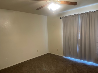Empty room with ceiling fan and dark carpet