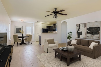 Living area with light tile patterned flooring, arched walkways, and a ceiling fan
