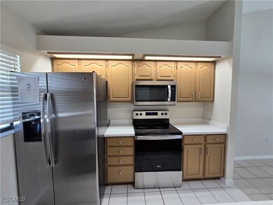 Kitchen featuring appliances with stainless steel finishes, light countertops, light tile patterned floors, and lofted ceiling