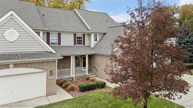 View of front of home with brick siding, covered porch, a shingled roof, a garage, and a front lawn