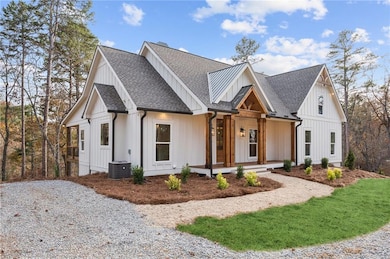 Modern farmhouse with roof with shingles, a porch, and board and batten siding