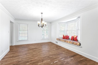 Unfurnished dining area with crown molding, a textured ceiling, dark wood-style floors, and a chandelier