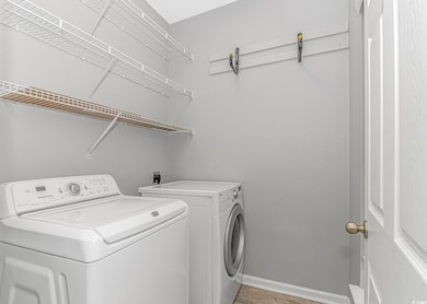 Laundry area featuring washing machine and clothes dryer, baseboards, and light wood-type flooring