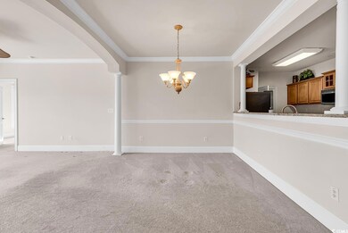 Unfurnished dining area featuring ornamental molding, light colored carpet, arched walkways, ornate columns, and a chandelier