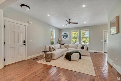 Living area with light wood-style floors, recessed lighting, ceiling fan, and a textured ceiling