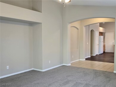 Tiled spare room featuring baseboards, arched walk