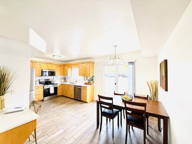 Kitchen with light countertops, appliances with stainless steel finishes, a chandelier, decorative light fixtures, and light wood-style flooring