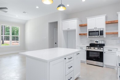 Kitchen featuring open shelves, concrete flooring,