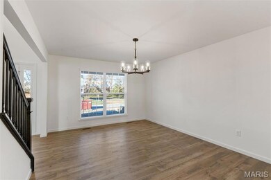 Unfurnished dining area featuring wood finished floors, a chandelier, and stairs