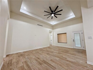 Unfurnished living room with ceiling fan, a raised ceiling, light wood-style floors, baseboards, and recessed lighting