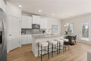 Kitchen with tasteful backsplash, appliances with stainless steel finishes, a breakfast bar, light wood-style floors, and white cabinetry