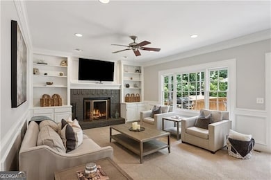 Living area featuring a ceiling fan, a fireplace, built in features, a wainscoted wall, and recessed lighting