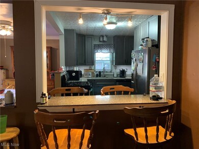 Kitchen with a kitchen bar, appliances with stainless steel finishes, ceiling fan, and light stone countertops