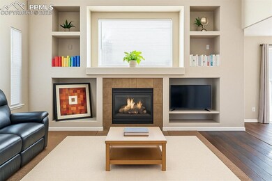 Living room with built in shelves, wood finished floors, baseboards, and a fireplace