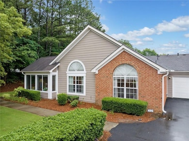 Ranch-style home featuring brick siding, an attached garage, a shingled roof, and driveway