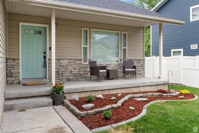 View of exterior entry featuring stone siding, a shingled roof, and covered porch