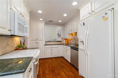 Kitchen featuring white appliances, visible vents, dark wood-style floors, white cabinetry, and a sink
