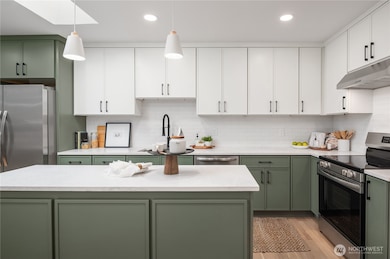 Full height upper cabinets, pendant lights and even an overhead skylight make this a memorable kitchen.