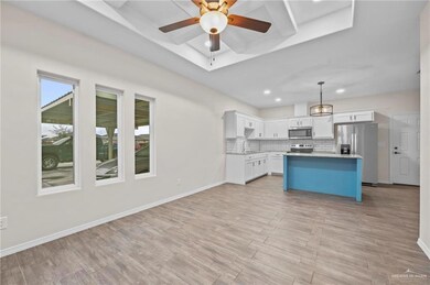 Kitchen featuring white cabinets, pendant lighting, stainless steel appliances, a center island, and light hardwood / wood-style flooring
