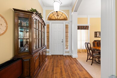 Foyer entrance with ornamental molding, decorative columns, arched walkways, and dark wood-type flooring