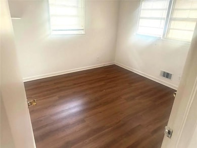 Empty room featuring plenty of natural light and dark hardwood / wood-style floors