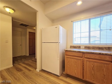 Kitchen with freestanding refrigerator, light wood finished floors, and brown cabinets