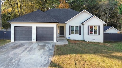 Ranch-style home featuring concrete driveway, a garage, crawl space, roof with shingles, and view of wooded area