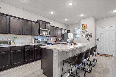 Kitchen with stainless steel appliances, light countertops, a breakfast bar area, tasteful backsplash, and an island with sink