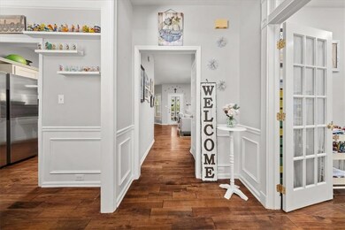 Hall with dark wood-type flooring, a decorative wall, and wainscoting